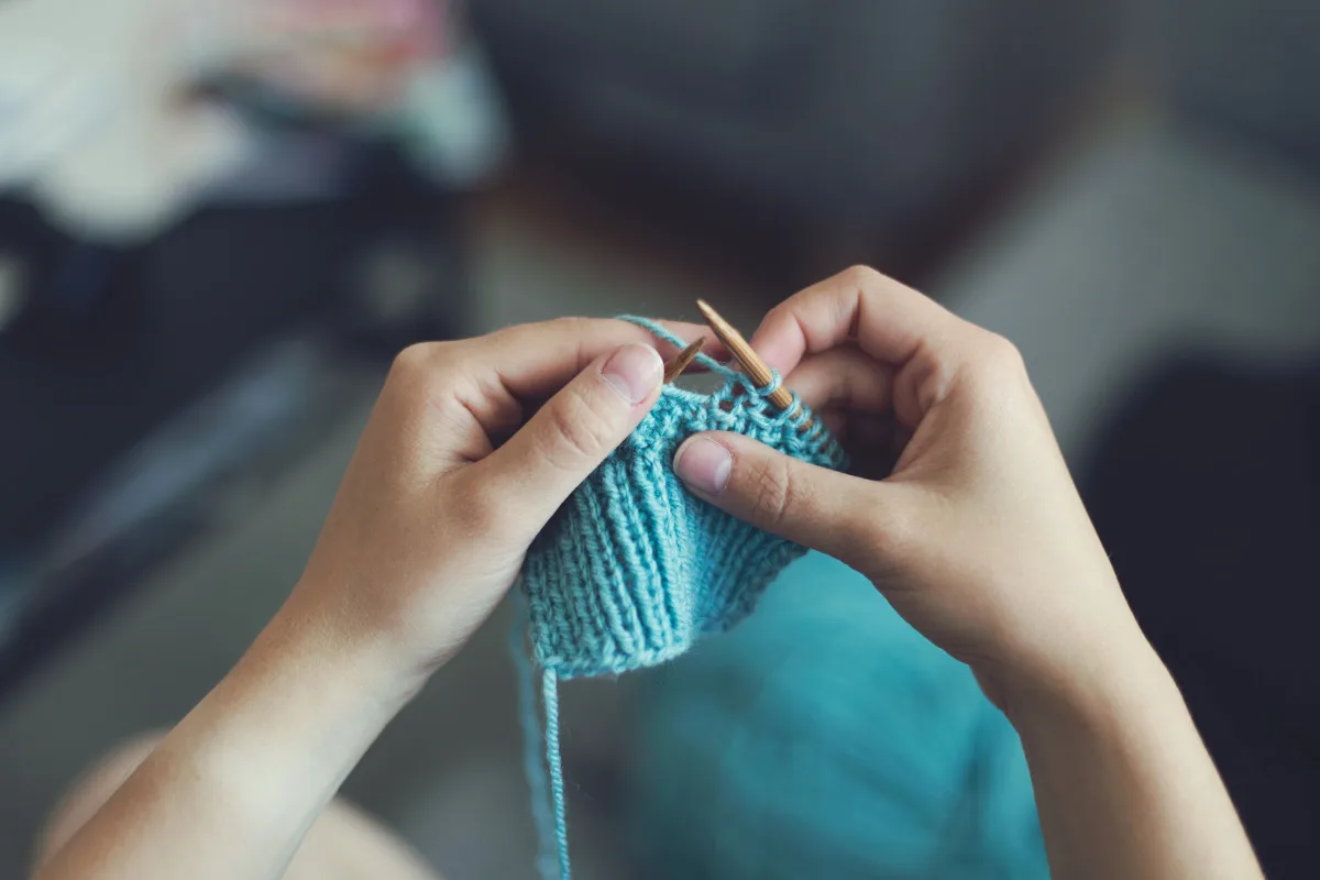 Hands working with needle, thread and fabric at a sewing table